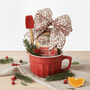 Red mug with muffin mix, festive bow, and Christmas decorations on a white background