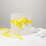 White gift box with a yellow ribbon on a light gray background