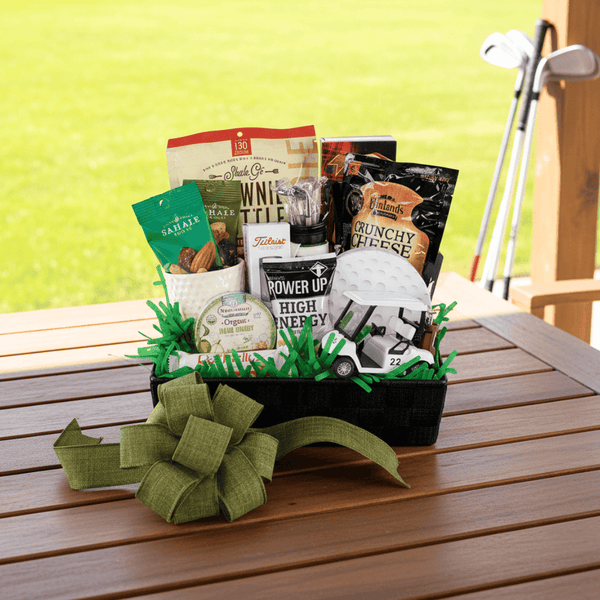 Golf themed gift basket with snacks on a wooden table with golf clubs in the background