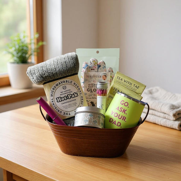 Gift basket with various items including a mug, tea, and relaxation products on a wooden table.