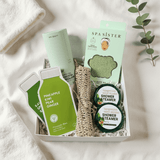 Spa products including facial masks, a scrubber, a jade facial roller and shower steamers in a box on a white background