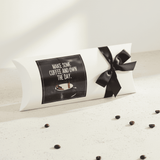 Decorative pillow with a black bow and coffee-themed design on a light surface.