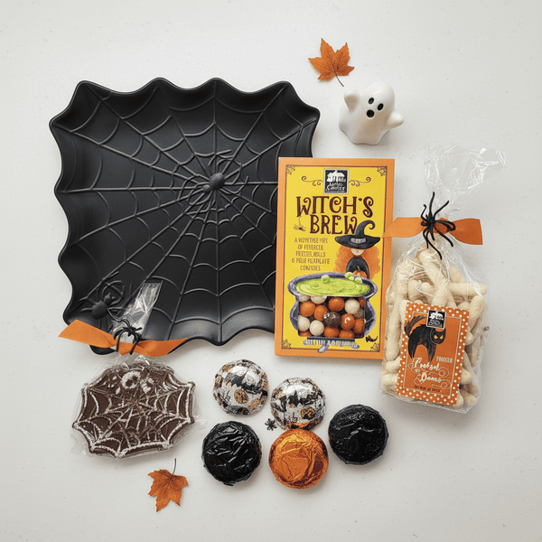 Halloween-themed treats and decorations including a spider web plate, candy, and packaging on a white background.