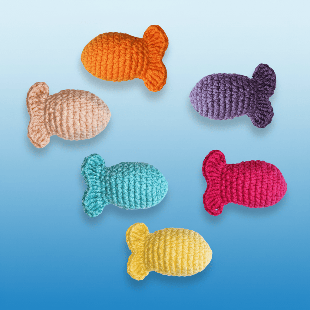 Set of colorful Bruiser McKitty crocheted fish toys on a blue background